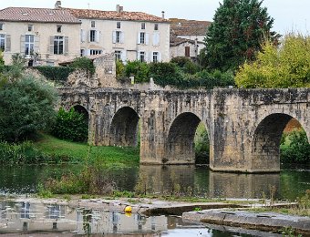 Le pont roman vue de l'amont. Au premier plan l'ouverture du plan incliné permettant aux kayacs de franchir le barrage  C' était un lieu de passage très important au moyen-âge. Il est construit en pierre et possède neuf arches. Le moulin a été fortifié afin de surveiller ce passage et pour servir de point de péage. Le pont était très certainement défendu également par un pont-levis